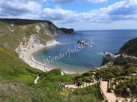 Plage de Durdle Door en Angleterre, avec des falaises blanches et une mer calme.