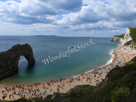 Plage animée avec des baigneurs et l'arche de Durdle Door, Angleterre.
