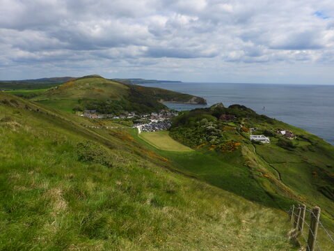 Vue panoramique sur Durdle Door en Angleterre, avec des collines verdoyantes et la mer en arrière-plan.