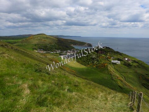 Vue panoramique sur Durdle Door en Angleterre, avec des collines verdoyantes et la mer en arrière-plan.