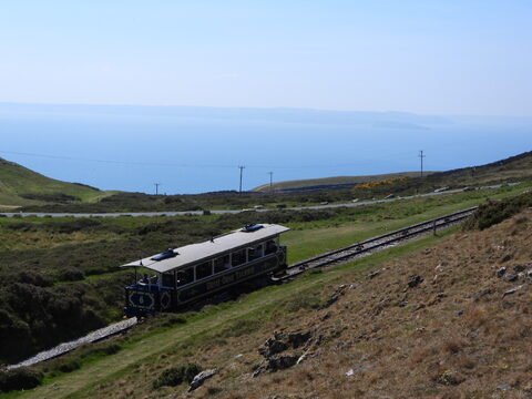Tramway sur rails dans les collines de Llandudno, Pays de Galles, avec vue sur la mer et le paysage environnant.