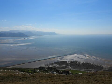 Vue sur la mer et les côtes de Llandudno, au pays de Galles, avec des montagnes en arrière-plan et un rivage sablonneux.