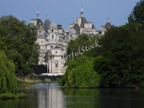 Bâtiment historique au bord d'un plan d'eau à Londres, Angleterre, entouré d'arbres et de verdure.