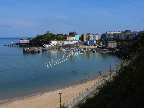 Bateaux dans le port de Tenby, au pays de Galles, entourés de maisons colorées et d'une plage de sable.