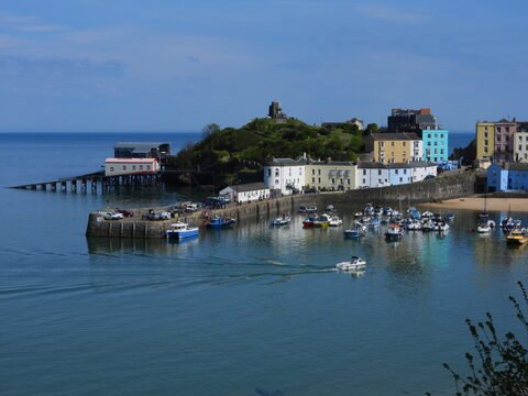 Port de Tenby au pays de Galles, avec des bateaux amarrés et des maisons colorées en arrière-plan.