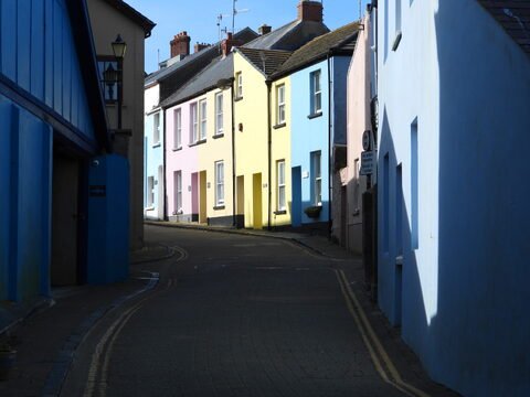 Des maisons colorées le long d'une ruelle à Tenby, pays de Galles, avec des façades bleu, rose et jaune.