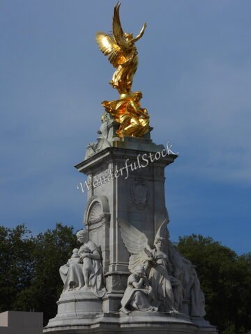 Statue dorée d'un ange sur un monument, Londres, Angleterre, avec des sculptures en marbre en bas.