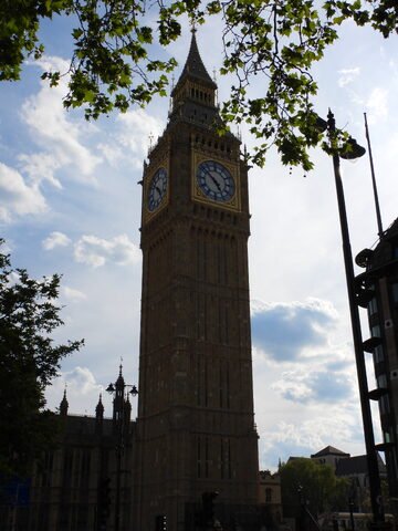 Big Ben à Londres, Angleterre, avec un ciel nuageux et des arbres en premier plan.