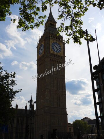 Big Ben à Londres, Angleterre, avec un ciel nuageux et des arbres en premier plan.