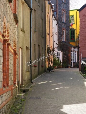 Ruelle étroite à Tenby, pays de Galles, avec des façades colorées et des pots de fleurs.