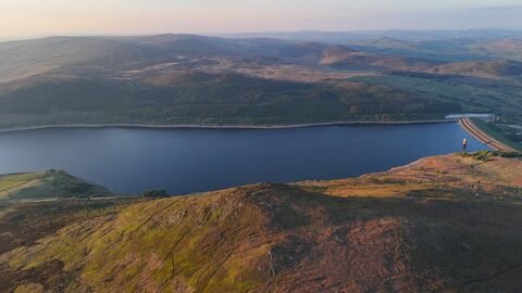 Vue aérienne d'un lac entouré de collines verdoyantes en Angleterre, Pays de Galles.