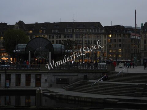 Bâtiment moderne avec des lumières et des passants à Hambourg, Allemagne, près d'un plan d'eau et d'escaliers.