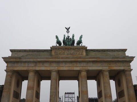 La porte de Brandebourg à Berlin, Allemagne, avec des sculptures de chevaux et des colonnes majestueuses sous un ciel nuageux.
