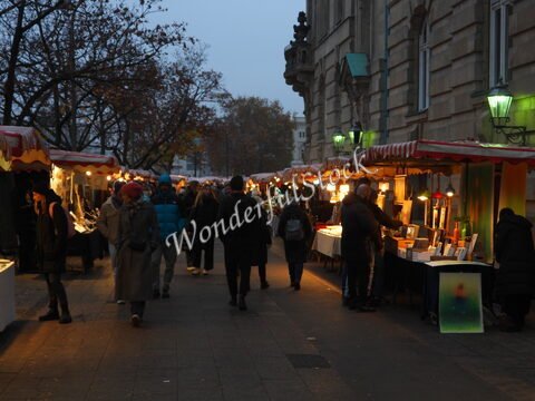 Marché animé à Berlin, Allemagne, avec des stands éclairés et des visiteurs se promenant sur une rue bordée d'arbres.