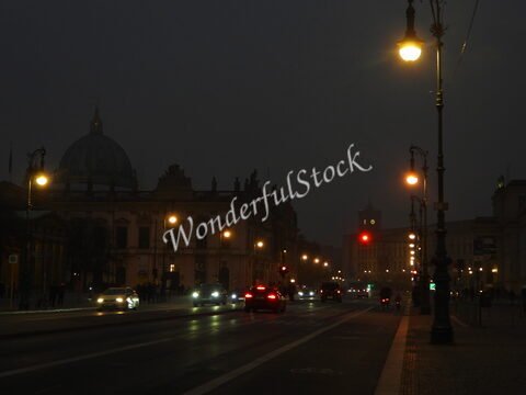 Lumières de la ville dans une rue de Berlin, Allemagne, avec un bâtiment historique et des voitures circulant dans l'obscurité.
