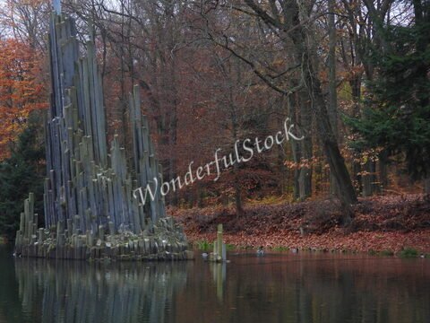 Piliers de pierre au bord d'un lac entouré d'arbres aux feuilles automnales, Allemagne.