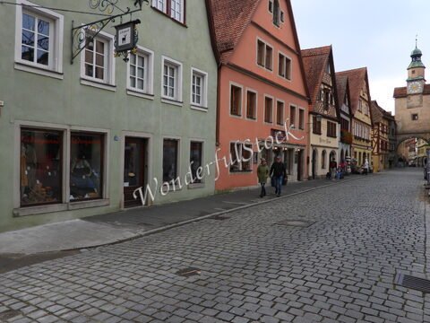 Rue pavée avec des maisons à colombages à Rothenburg, Allemagne, où se trouvent des boutiques et des passants.