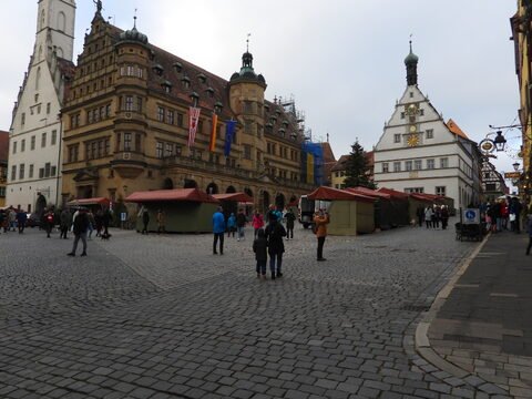 Place animée avec des bâtiments historiques à Rothenburg, Allemagne, incluant des tentes de marché et des pavés.