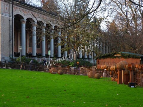 Bâtiment avec colonnes et artisans travaillant sur des décorations en bois à Baden-Baden, Allemagne, entouré de pelouse et d'arbres.