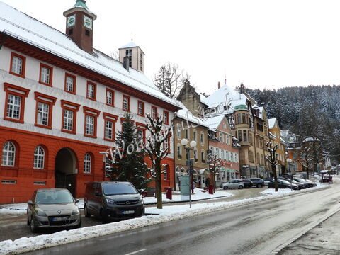Rue enneigée à Triberg, Allemagne, avec des bâtiments colorés et des arbres dénudés.