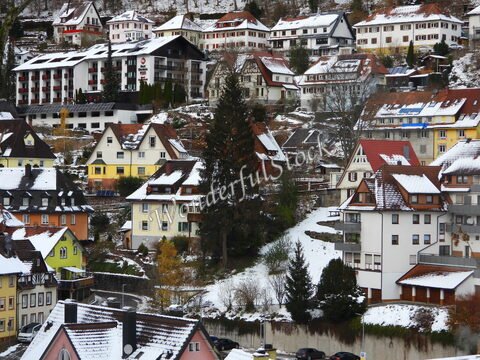Maisons colorées sous la neige à Triberg, Allemagne, avec des toits en pente et des arbres en arrière-plan.