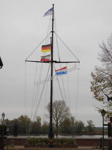 Mât avec les drapeaux allemand, luxembourgeois et européen à Hitzacker, Allemagne, avec un paysage fluvial en arrière-plan.