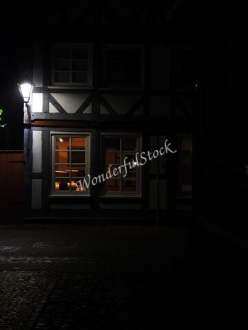 Maison à colombages éclairée la nuit à Hitzacker, Allemagne, avec des fenêtres illuminées et un lampadaire.