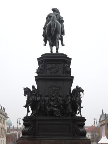 Monument équestre à Berlin, Allemagne, avec des personnages historiques en bronze sur la base, sous un ciel nuageux.