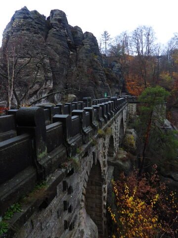 Pont de Bastei en Allemagne, entouré de rochers escarpés et de feuillage automnal.
