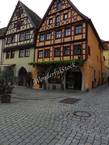 Maison à colombages avec un magasin à Rothenburg, Allemagne, entourée de pavés et de plantes grimpantes.