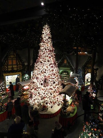 Un grand sapin de Noël décoré dans une boutique à Rothenburg, Allemagne, entouré de décorations festives et d'expositions d'artisanat.