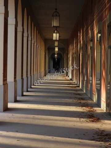 Couloir avec colonnes et lanternes à Munich, Allemagne, avec des ombres allongées et des feuilles au sol.