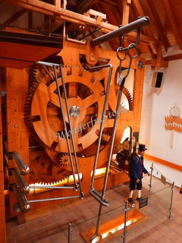 Mécanisme d'horloge en bois avec engrenages à Triberg, Allemagne, et une figurine en costume traditionnel à côté.