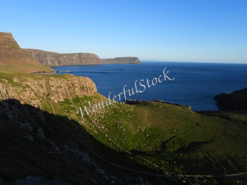 Côte escarpée et mer calme en Écosse. Des falaises verdoyantes surplombent l'océan, créant un paysage naturel distinctif.