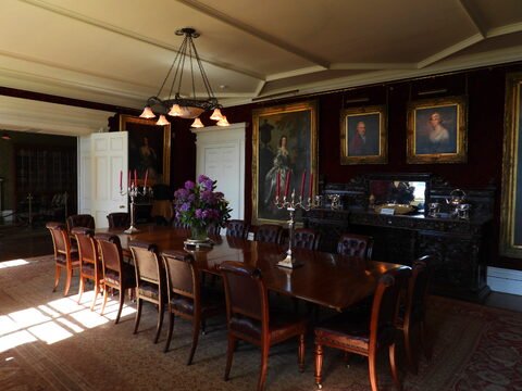 Salle à manger avec une grande table en bois, des portraits accrochés aux murs, Château de Dunvegan, Écosse.
