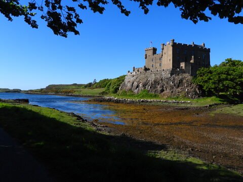 Château de Dunvegan en Écosse, avec un ciel dégagé et une rivière à proximité.