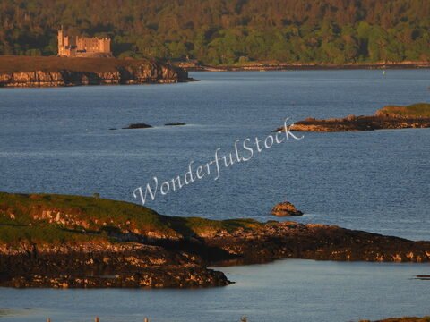 Château de Dunvegan, Écosse, avec des rochers et une mer calme en arrière-plan.