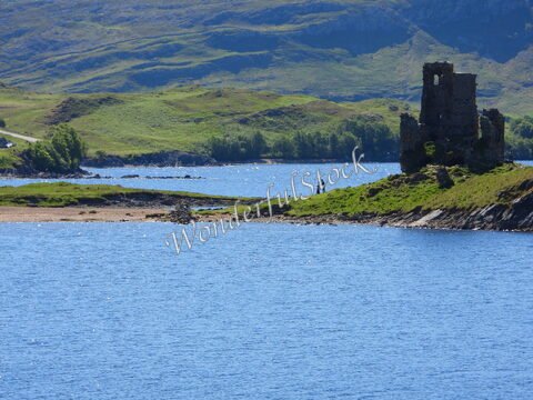 Ruines du château d'Ardvreck sur une île, avec des visiteurs, en Écosse.