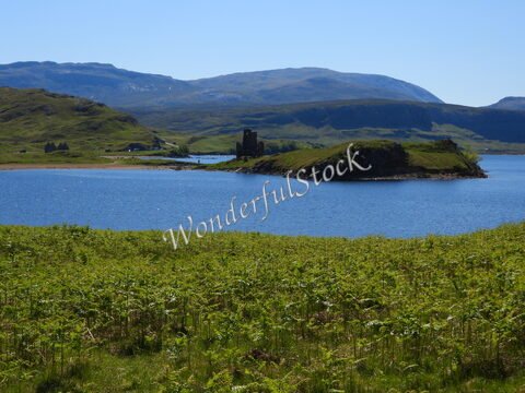 Ruines du château d'Ardvreck sur une île, entourées d'eau et de collines, en Écosse.