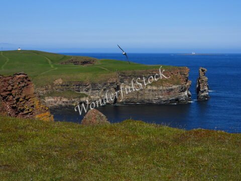 Falaises de Duncansby Head en Écosse, avec une mer calme et un ciel dégagé.