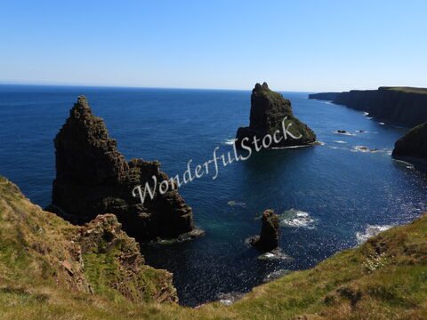 Scènes côtières à Duncansby Head, Écosse, avec des formations rocheuses distinctives émergeant de l'océan.