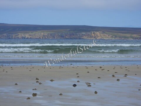 Plage de Dunnet Head en Écosse, avec des vagues et des traces sur le sable.