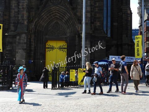 Foule animée devant un bâtiment avec une grande porte jaune à Édimbourg, Écosse, lors d'un événement festif.