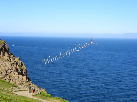 Vue sur la mer depuis une falaise avec des visiteurs, Île de Skye, Écosse. Un bateau navigue au loin.
