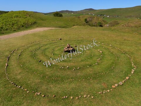 Un labyrinthe en pierres sur la pelouse, situé sur l'île de Skye, en Écosse, entouré de collines verdoyantes et d'une vue dégagée.