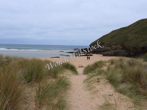 Plage de Strathy en Écosse, avec des dunes de sable et des personnes marchant le long de l'eau.