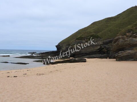 Plage de Strathy en Écosse, avec des rochers et une mer calme sous un ciel nuageux.