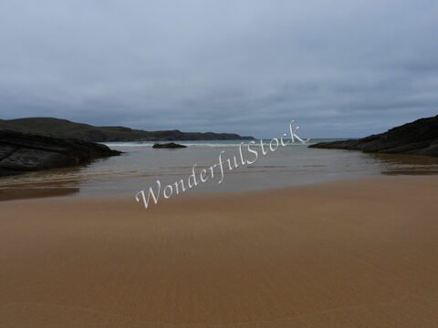 Plage de Strathy en Écosse, avec des rochers et un ciel nuageux.