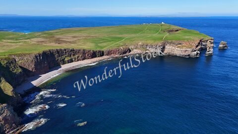 Duncansby Head en Écosse, avec des falaises surplombant une plage et l'océan en arrière-plan.