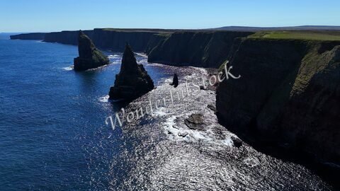 Falaises et formations rocheuses à Duncansby Head, Écosse, surplombant une mer scintillante.